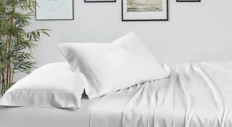Dormitorio moderno con sábanas de bambú blancas y decoración minimalista, reflejando los beneficios de dormir bien.