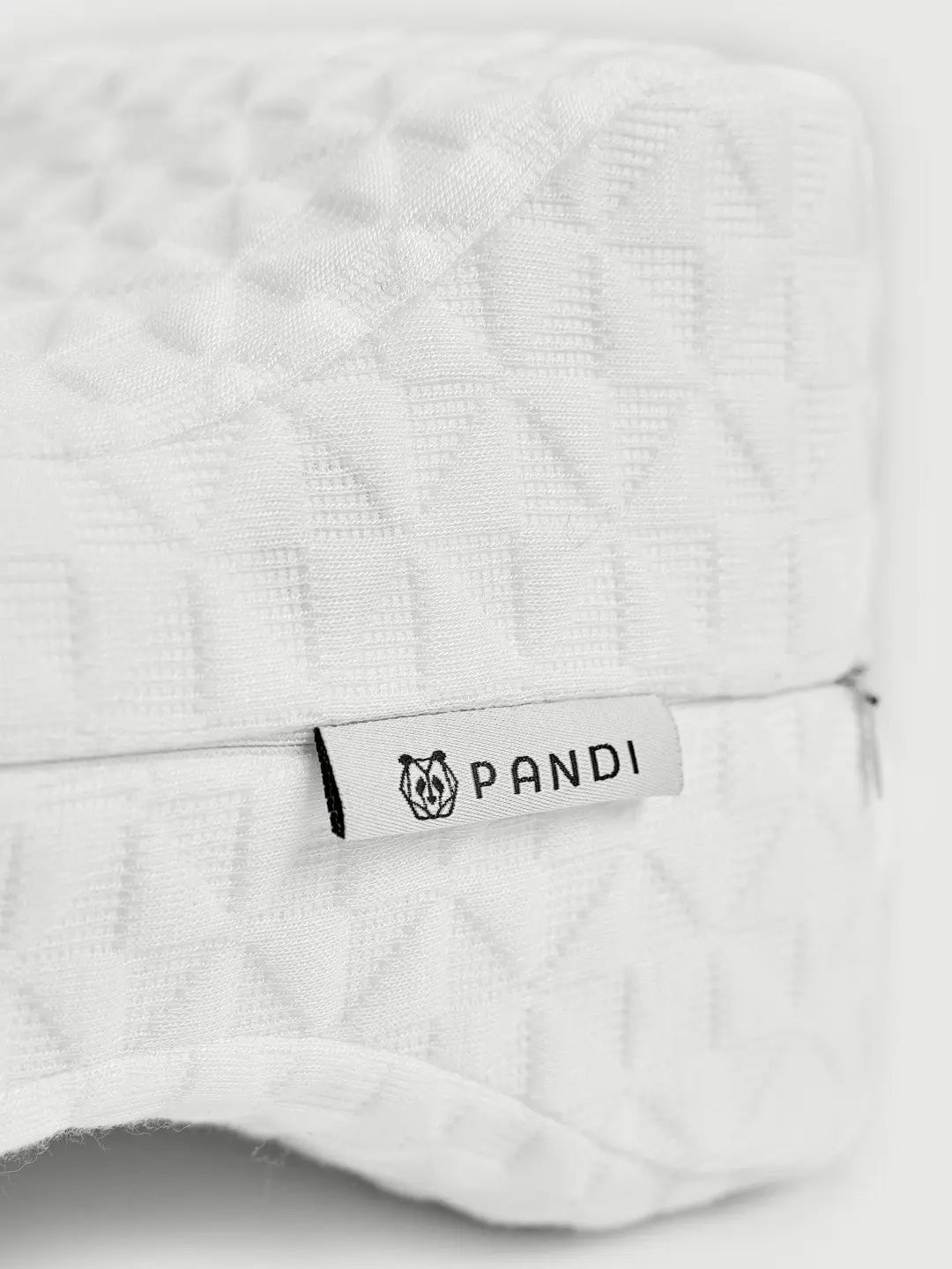 Primer plano de la almohada de rodilla de PANDI, destacando su etiqueta y material de calidad para un descanso reparador.