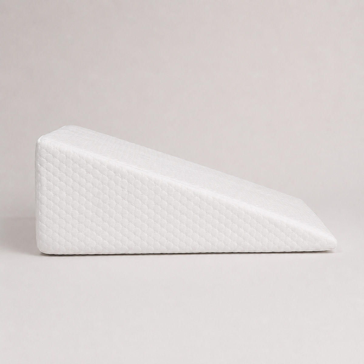 Almohada cuña PANDI de perfil, con funda acolchada blanca y pendiente suave, sobre fondo gris claro