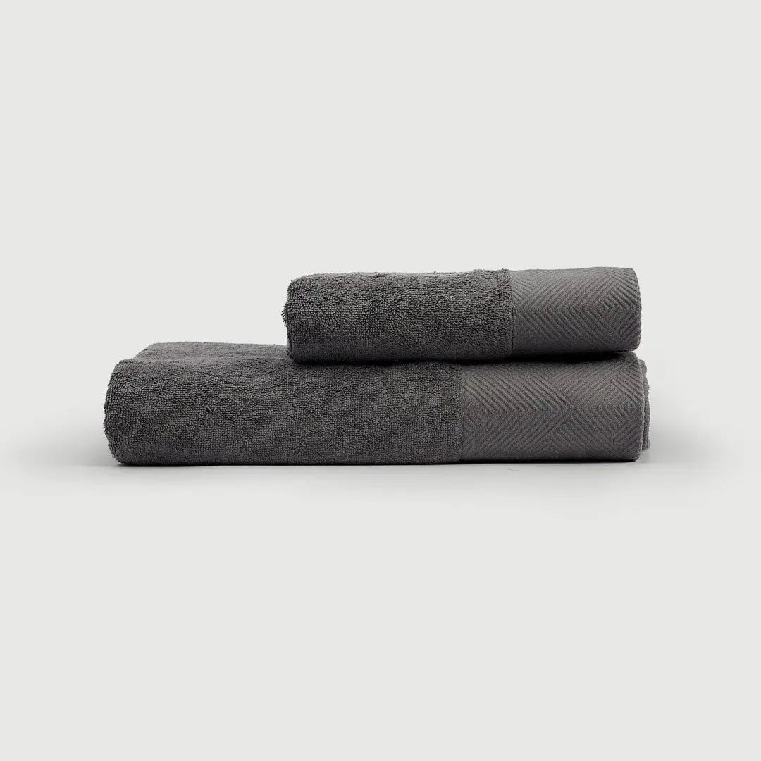 TOALLA DE MANO Gris Oscuro de PANDI, presentada en una pila elegante, destacando su calidad y confort.