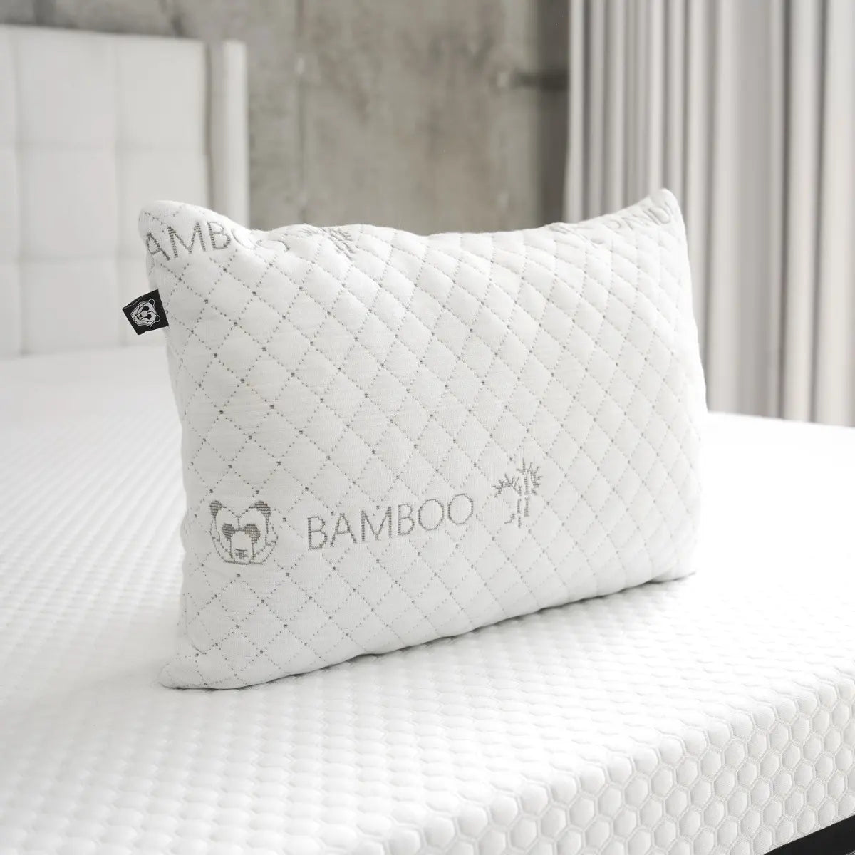 Almohada Lumbar Pandi, ergonómica y de bambú, ideal para aliviar el dolor de espalda, sobre una cama con colcha blanca, perfecta para el confort diario.