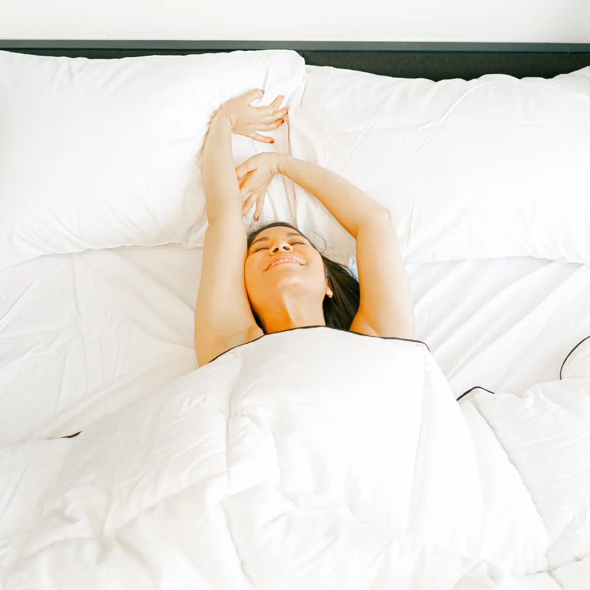 Mujer sonriente relajándose en la cama con sábanas de bambú, mostrando elegancia y comodidad en su experiencia de descanso, ideal para el blog 'Sábanas de Bambú: Elegancia, Comodidad y Cómo Elegirlas'.