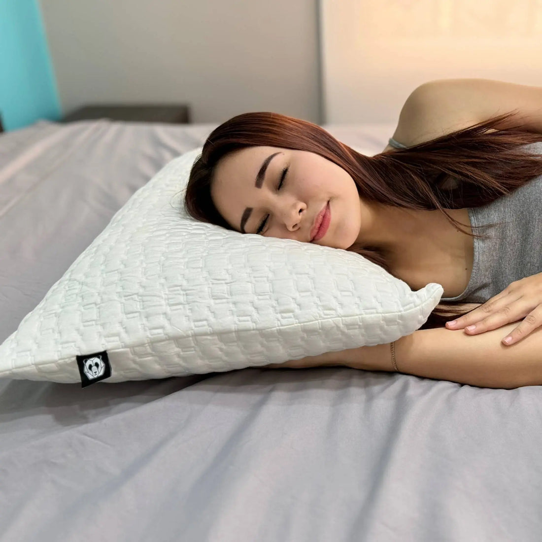 Mujer relajada durmiendo sobre una almohada ergonómica mientras disfruta de la fase REM del sueño, destacando la importancia de un descanso reparador.
