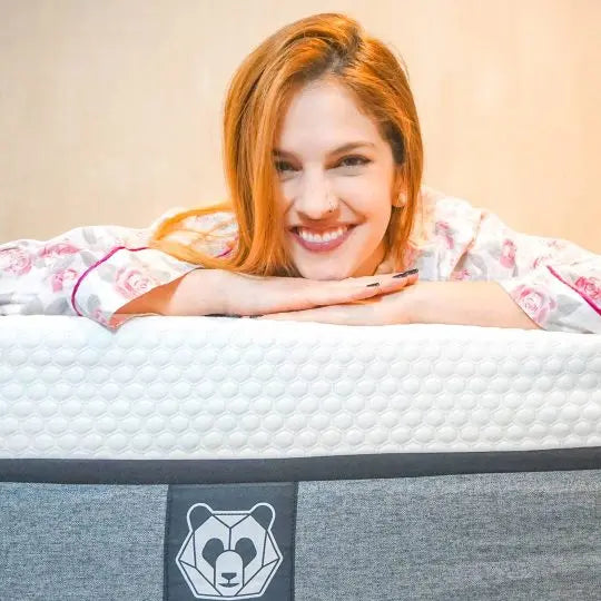 Descanso Ecológico: Una mujer sonriente posa sobre un colchón ortopédico de bambú de Pandi, destacando la comodidad y calidad de su descanso.