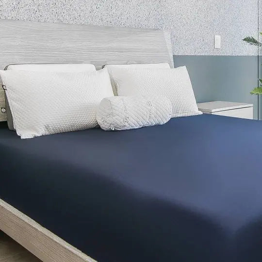 Transforma Tu Descanso con ropa de cama de lujo, mostrando un dormitorio moderno con sábanas de color azul oscuro, almohadas blancas y un toque de elegancia en un ambiente acogedor.