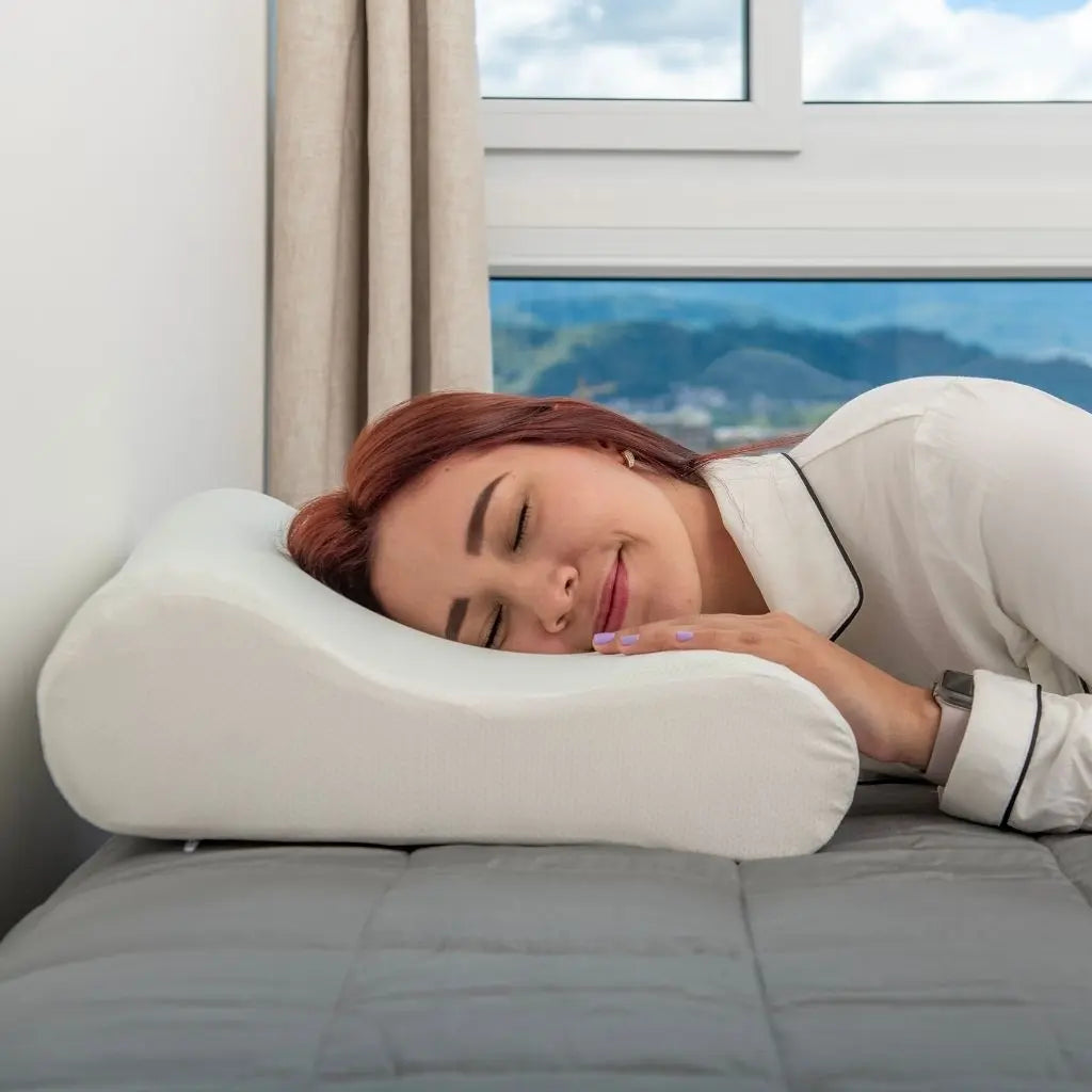 Mujer descansando cómodamente sobre una almohada curva de PANDI, disfrutando de un sueño reparador en un entorno luminoso y acogedor. Almohadas diseñadas para garantizar el descanso ideal y el soporte ortopédico.