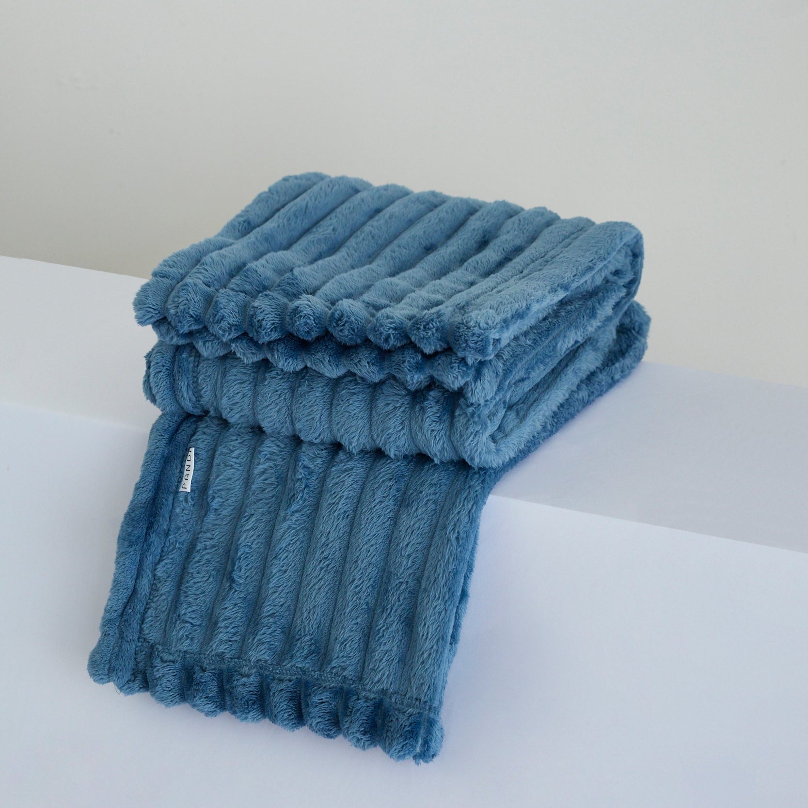 Manta Cuzy - Azul, una manta de franela suave que combina calidez y elegancia para disfrutar en cualquier momento.