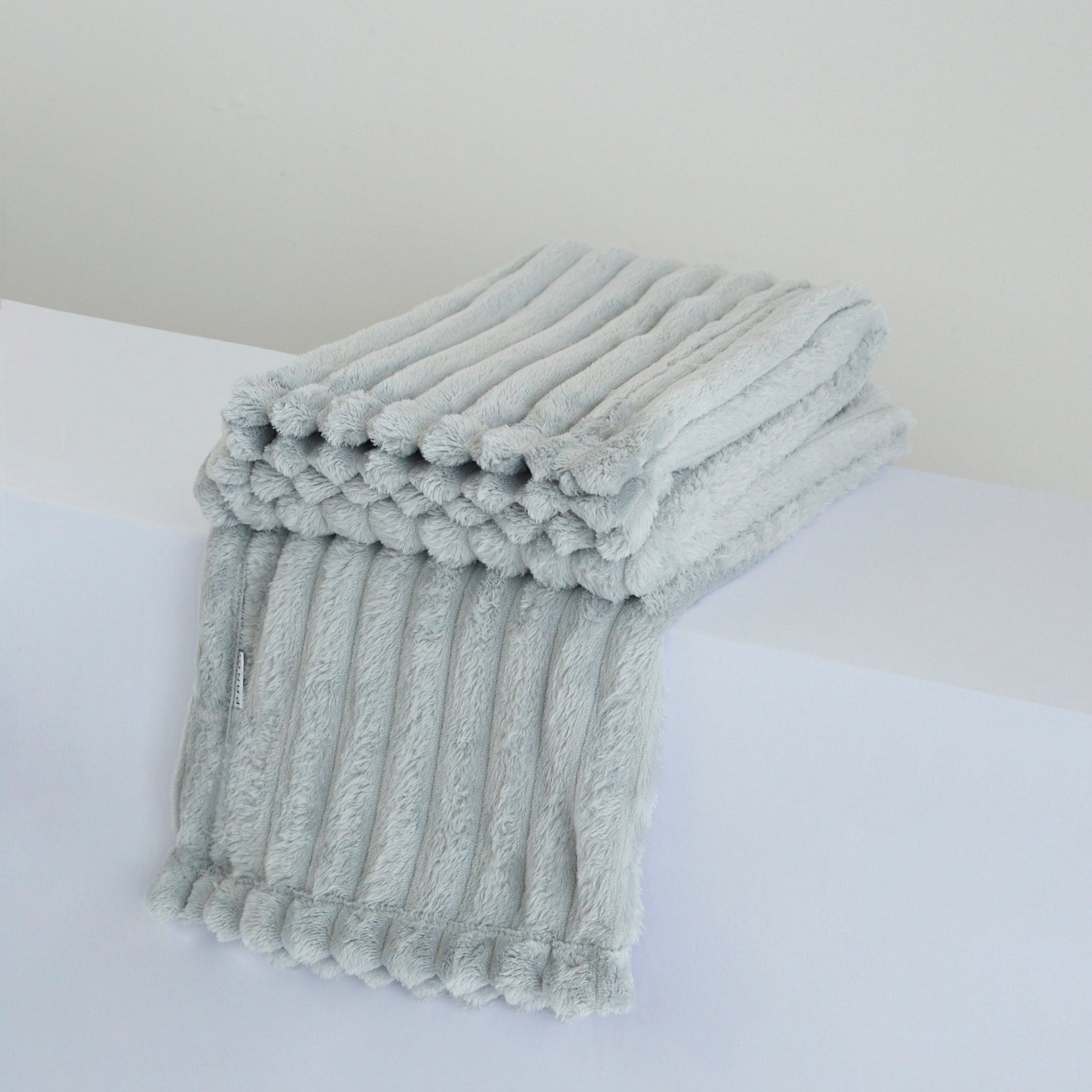 Manta Cuzy - Gris, una suave y cálida manta de franela ideal para abrigarse en cualquier ocasión.