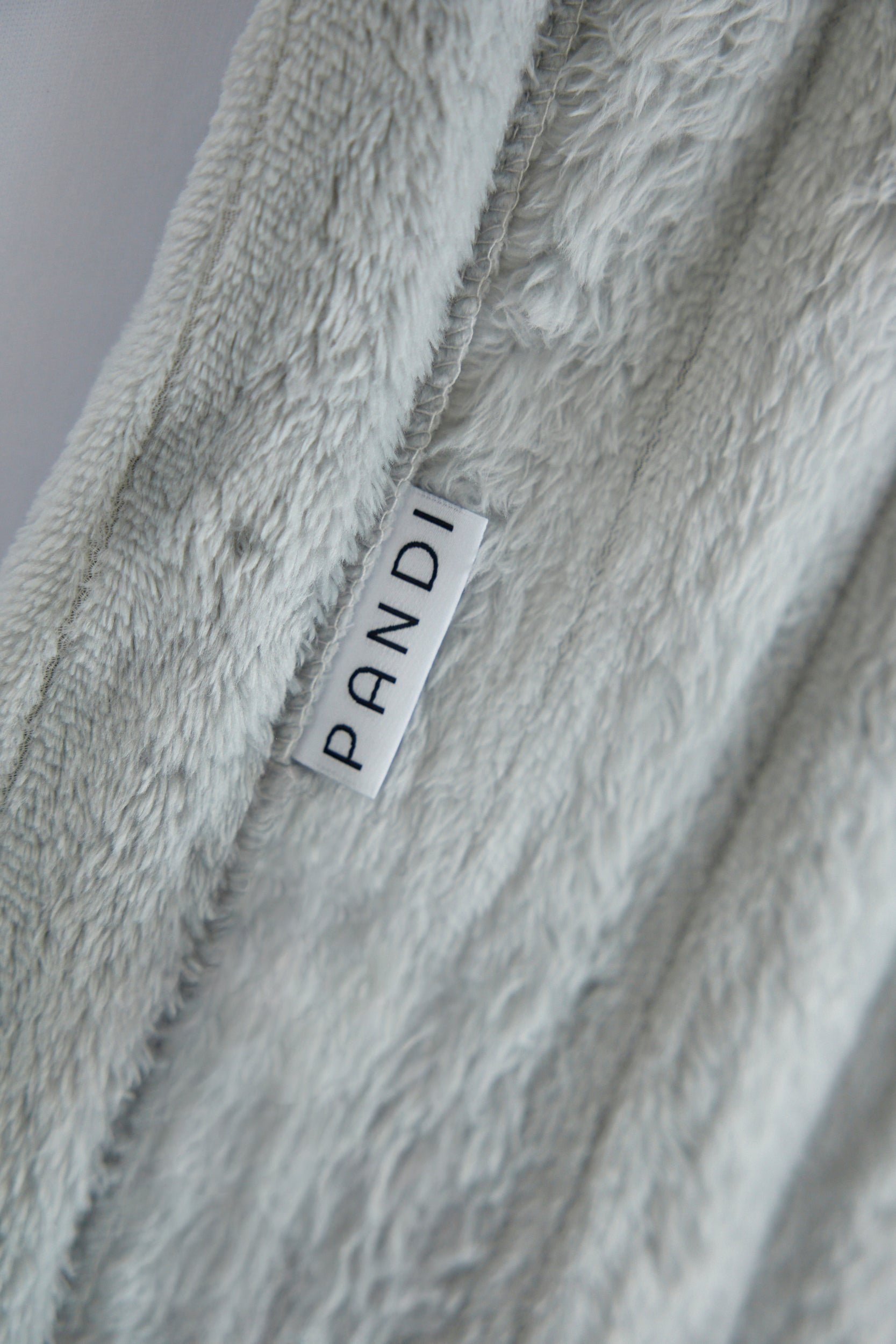 Detalles de la Manta Cuzy - Gris, mostrando su textura aterciopelada y diseño elegante, perfecta para tu hogar.