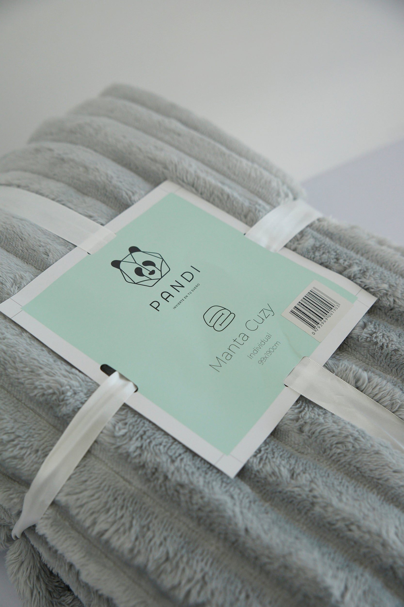 Manta Cuzy - Gris plegada, destacando su fácil almacenamiento y portabilidad para viajes y picnics.