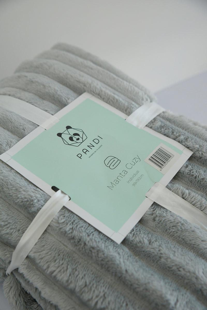 Manta Cuzy - Gris plegada, destacando su fácil almacenamiento y portabilidad para viajes y picnics.