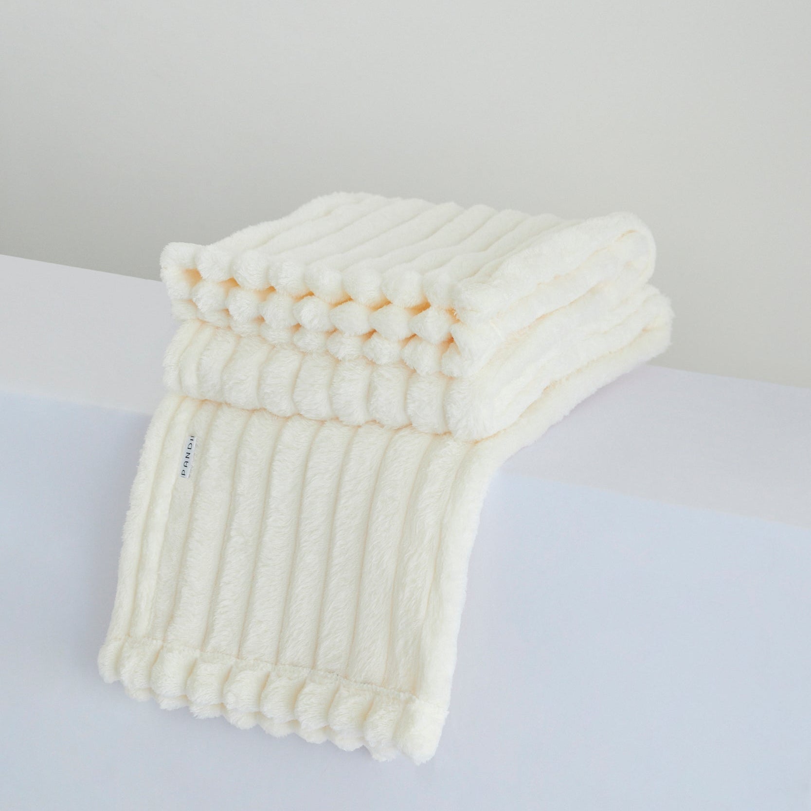 Manta Cuzy - Crema, la manta de franela suave ideal para descansar y disfrutar de confort en cualquier momento del día.