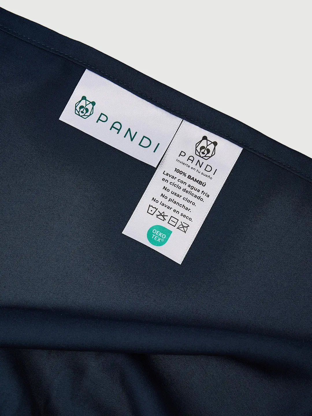 Etiqueta del Set de Sábanas 100% Bambú de PANDI en azul marino, con instrucciones de lavado y certificaciones, mostrando la calidad y cuidado del producto para un descanso óptimo.