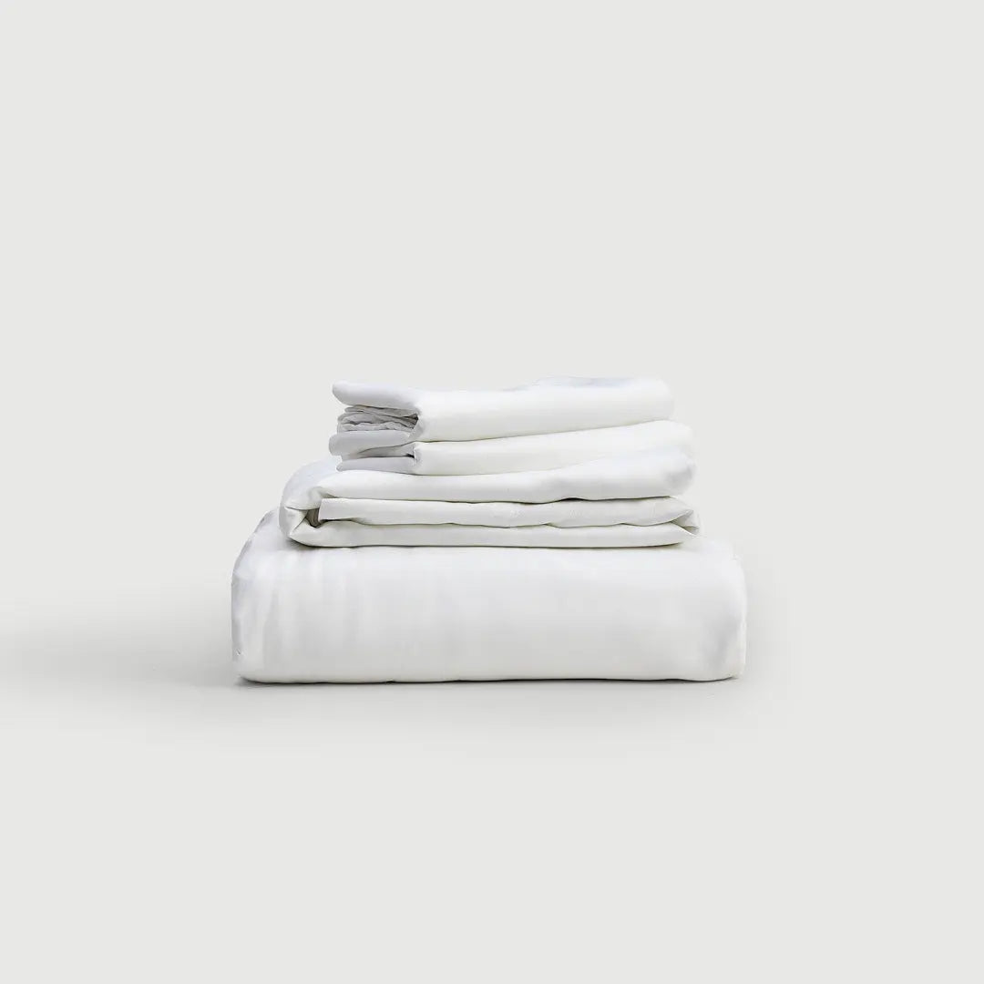 Set de sábanas 100% bambú PANDI en color blanco, apiladas elegantemente sobre un fondo suave. Perfectas para un descanso lujoso y cómodo.