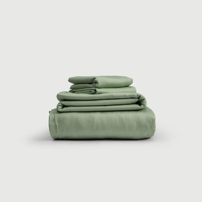 Set de sábanas 100% bambú en vibrante color verde, apiladas de manera organizada, ideales para un descanso reparador.