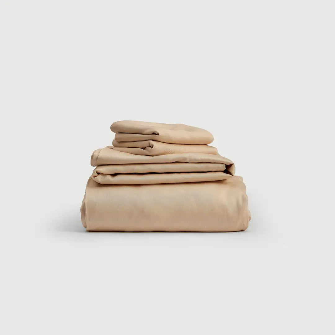 Set de sábanas 100% bambú en color beige, apiladas de manera ordenada, ofreciendo una apariencia elegante y suave para un descanso reparador.