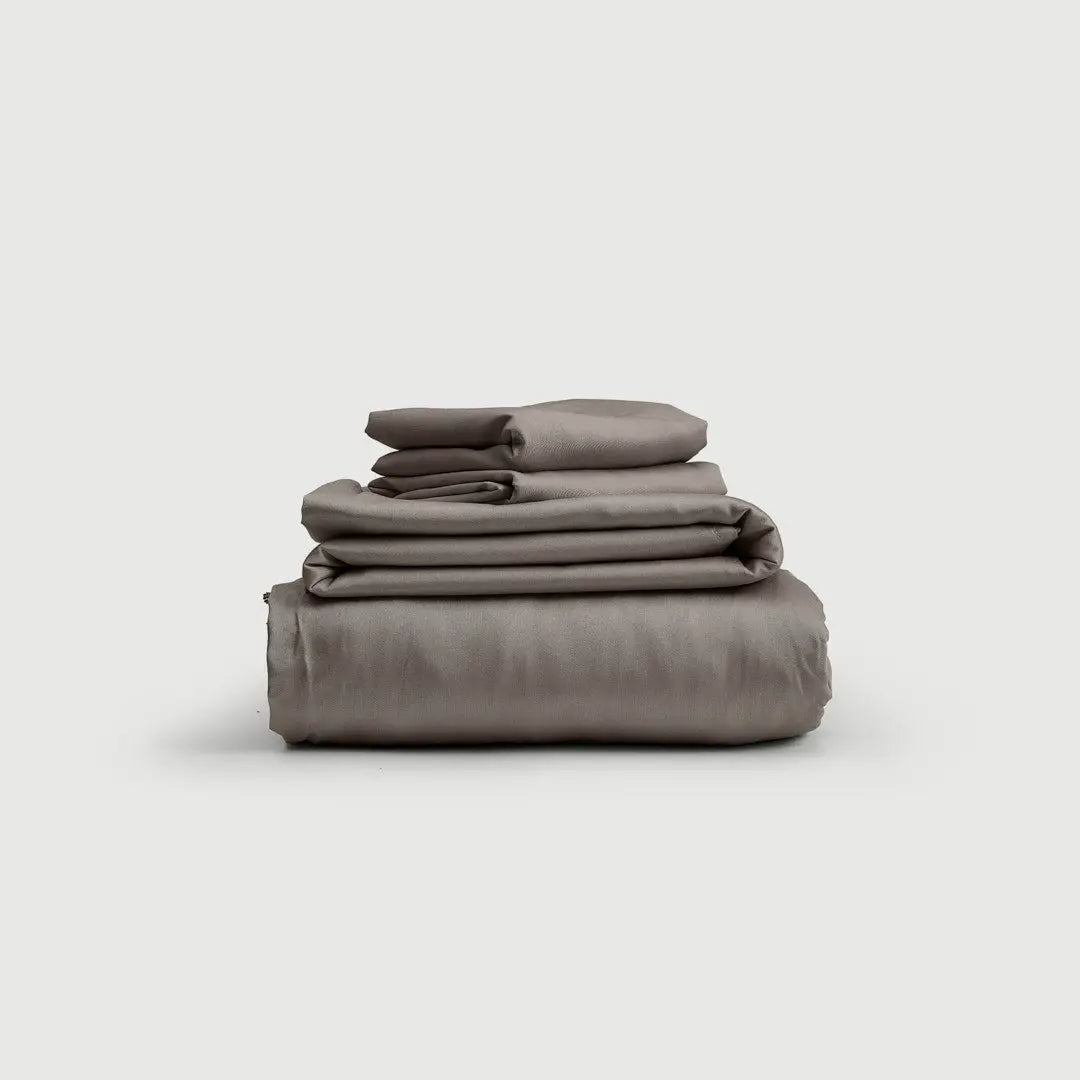 Set de Sábanas 100% Bambú en Gris Oscuro, exhibido en su elegante presentación, destacando la suavidad y frescura que ofrece para un descanso reparador.