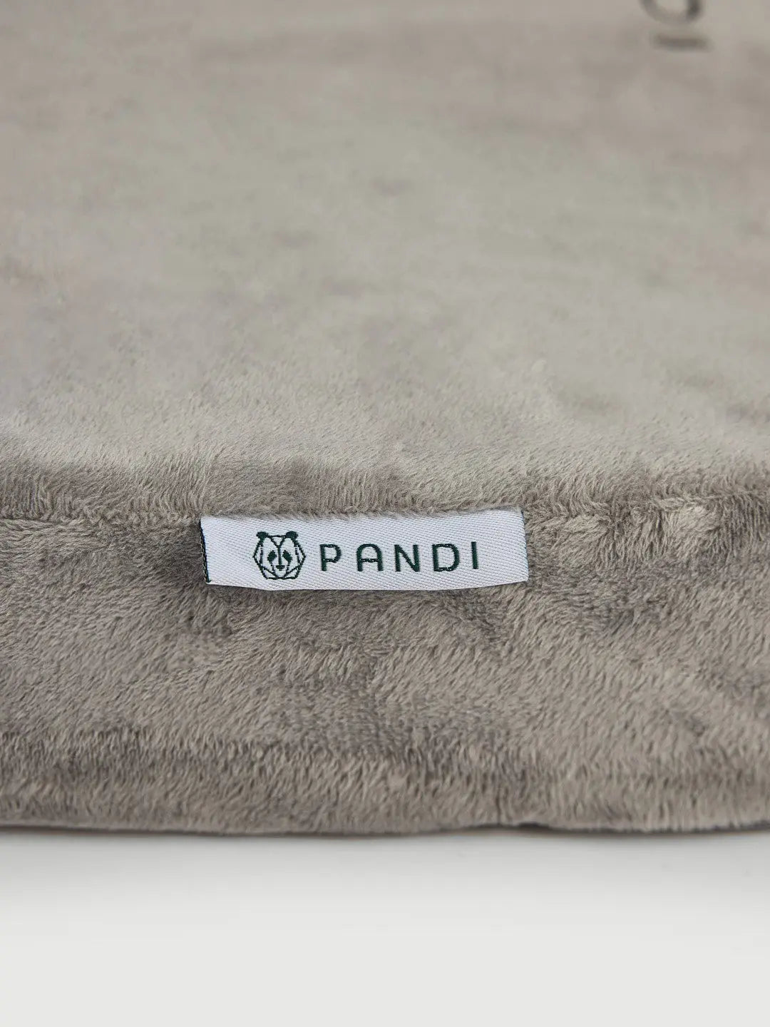 Cojín de Asiento Ortopédico de PANDI con textura suave y etiqueta que destaca la marca, ideal para proporcionar comodidad y soporte ergonómico.