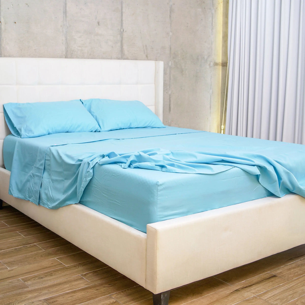 Juego de sábanas de 60% bambú en color celeste, colocado sobre una cama moderna con cabecera blanca, mostrando su suavidad y elegancia, ideal para un descanso confortable.